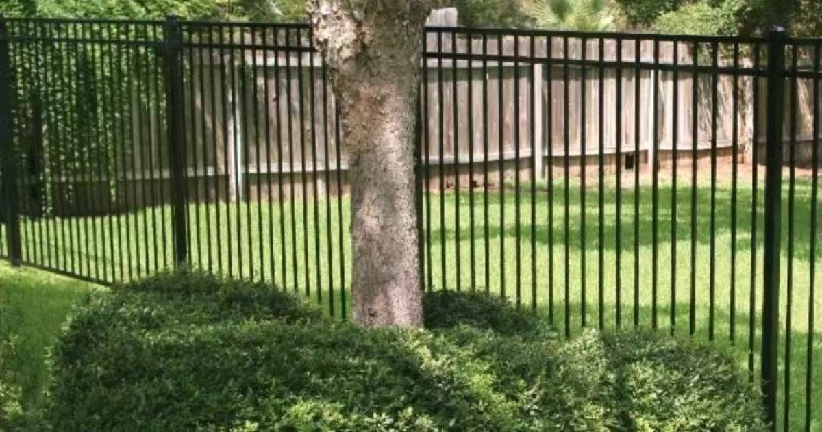 Open black garden fence installed beside a lawn and trees