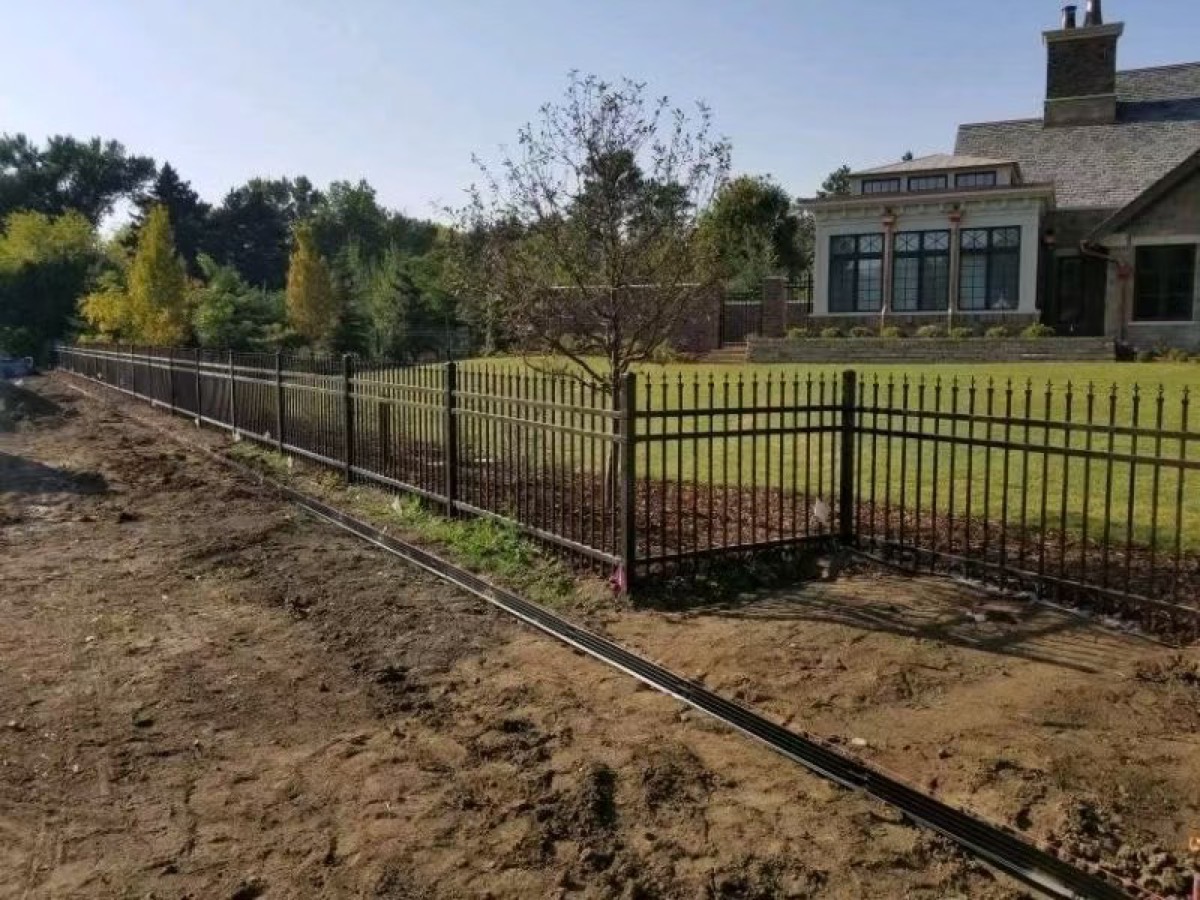 Long black vertical-picket fence along a landscaped property boundary