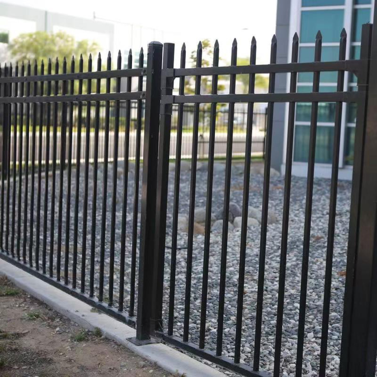 Close view of black fence bars, horizontal rails, and a fixed post