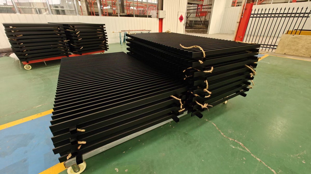 Black coated gate and fence components grouped on factory carts